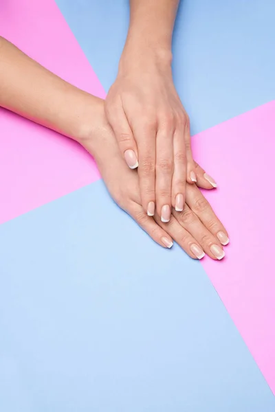 Mãos femininas bonitas com manicure francês sobre fundo de papel colorido — Fotografia de Stock