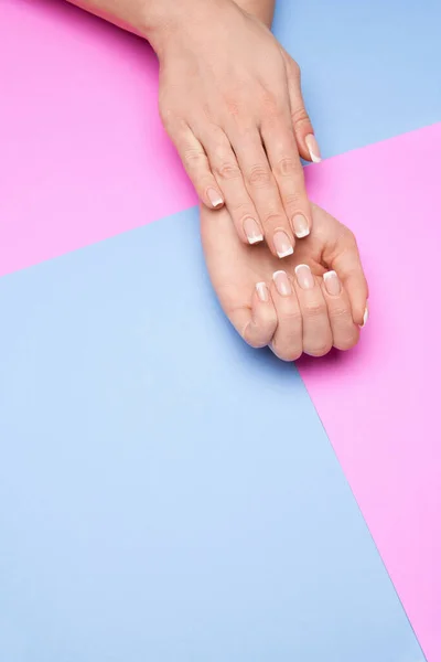 Mãos femininas bonitas com manicure francês sobre fundo de papel colorido — Fotografia de Stock