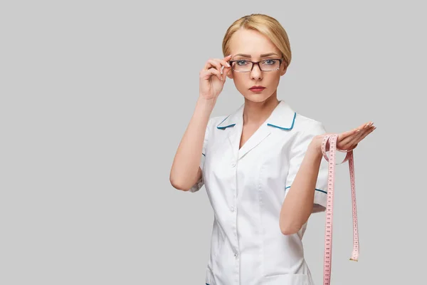 Fröhliche Ärztin oder Krankenschwester mit Maßband vor grauem Hintergrund — Stockfoto