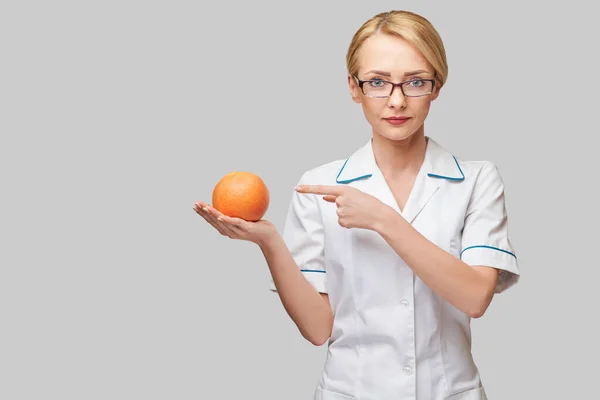 Nutritionist doctor healthy lifestyle concept - holding organic grapefruit or orange fruit — Stock Photo, Image