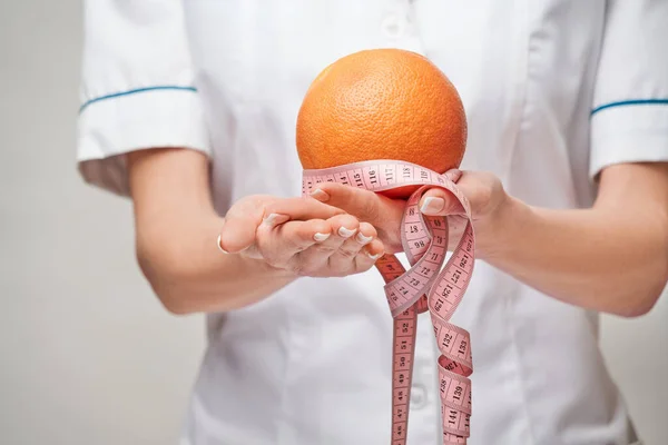 Дієтолог концепція здорового способу життя - тримає органічний грейпфрут або апельсиновий фрукт і мірну стрічку — стокове фото