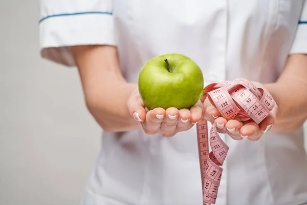 Дієтолог концепція здорового способу життя - тримає органічне свіже зелене яблуко і мірну стрічку — стокове фото