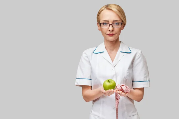 Nutricionista médico conceito de estilo de vida saudável - segurando maçã verde fresca orgânica e fita métrica — Fotografia de Stock