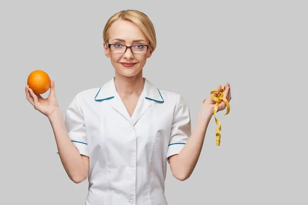 Nutricionista médico conceito de estilo de vida saudável - segurando fruta laranja fresca orgânica e fita métrica — Fotografia de Stock