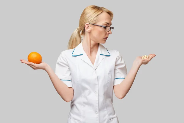 Nutricionista médico conceito de estilo de vida saudável - segurando frutas frescas laranja orgânica e cápsulas de vitaminas — Fotografia de Stock
