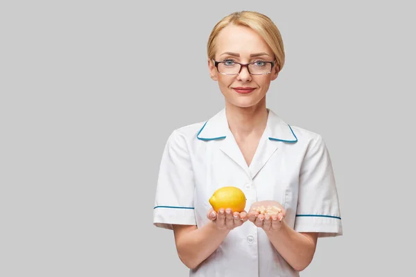 Nutricionista médico conceito de estilo de vida saudável - segurando frutas frescas limão orgânico e cápsulas de vitaminas — Fotografia de Stock