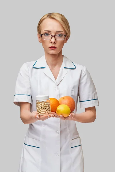 Nutricionista médico concepto de estilo de vida saludable - celebración de cítricos orgánicos frescos - pomelo, naranja, limón y lata de cápsulas vitamínicas —  Fotos de Stock