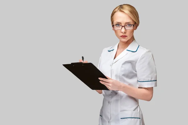 Krásná žena lékař držení schránky izolované na šedém pozadí — Stock fotografie
