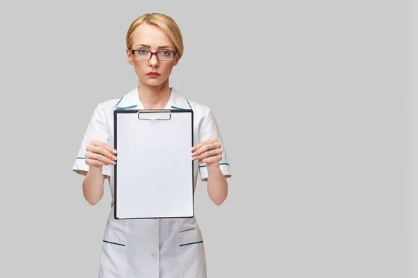 Hermosa doctora sosteniendo portapapeles aislado sobre fondo gris —  Fotos de Stock