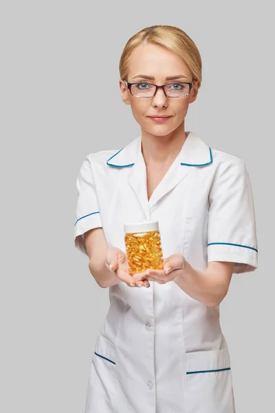 Hälso- och sjukvård och kost koncept - läkare dietist eller kardiolog håller fiskolja i kapslar för vitamin D och omega-3 fettsyror — Stockfoto