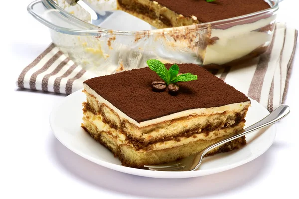 Tradycyjny włoski deser Tiramisu w szklanym naczyniu do pieczenia, porcja na talerzu i łopatce izolowana na białym tle — Zdjęcie stockowe