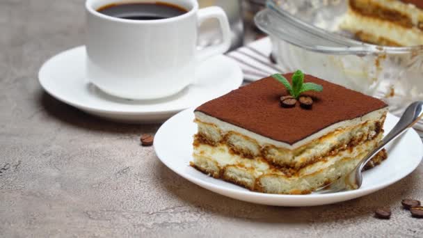 Postre Tiramisú tradicional italiano en bandeja para hornear de vidrio y porción sobre fondo de hormigón gris — Vídeo de stock