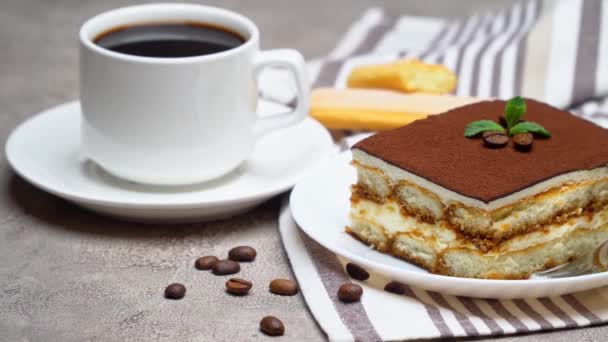 Portion traditionelles italienisches Tiramisu-Dessert und Tasse Kaffee auf grauem Betongrund — Stockvideo