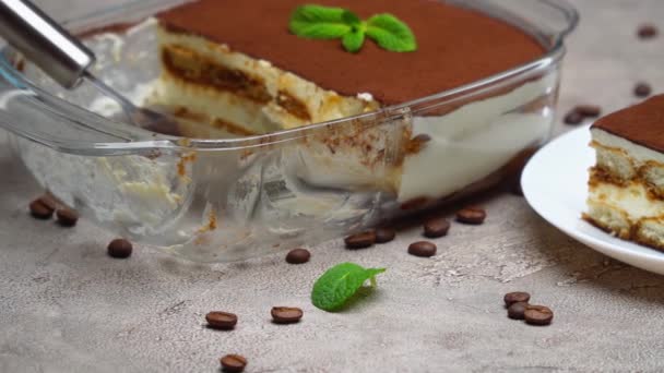 伝統的なイタリアのティラミスのデザートは、ガラス製のベーキング皿と灰色のコンクリートの背景の部分 — ストック動画