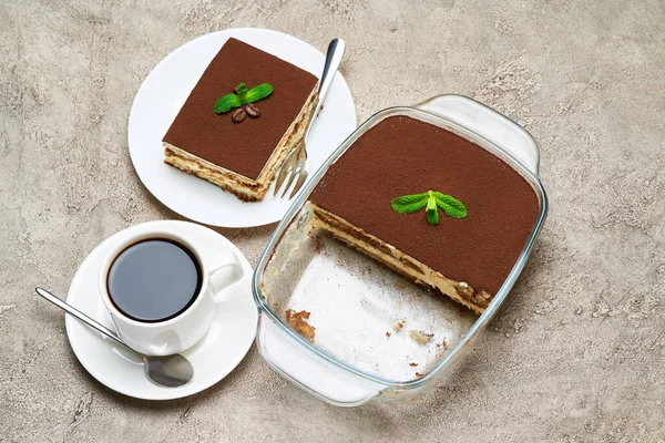 Postre Tiramisú tradicional italiano en bandeja para hornear de vidrio y porción sobre fondo de hormigón gris —  Fotos de Stock