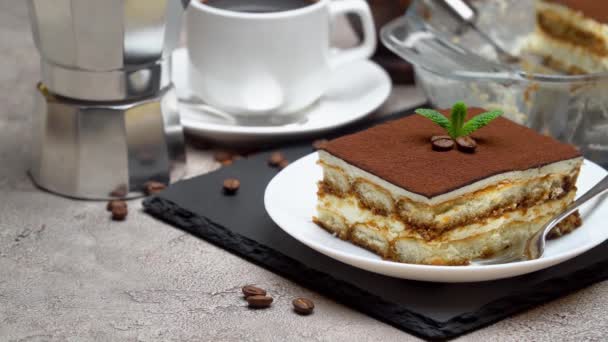 Dessert tradizionale Tiramisù italiano in teglia di vetro e porzione su fondo grigio cemento — Video Stock