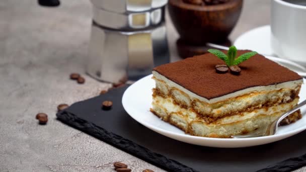 Portie traditioneel Italiaans Tiramisu dessert en mokka koffiezetapparaat op grijze betonnen ondergrond — Stockvideo