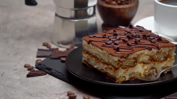 Portie traditioneel Italiaans Tiramisu dessert en mokka koffiezetapparaat op grijze betonnen ondergrond — Stockvideo