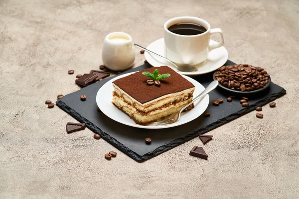 Porcja tradycyjnego włoskiego deseru Tiramisu i filiżanka kawy espresso na szarym betonowym tle — Zdjęcie stockowe