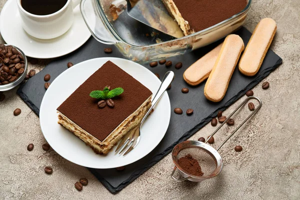 Portion traditionelles italienisches Tiramisu-Dessert und Mokkakaffeemaschine auf grauem Betongrund — Stockfoto