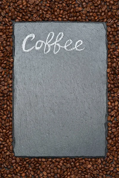 Fondo o textura hecha de granos de café tostados marrón y tabla de servir de piedra con tiza letrero escrito a mano — Foto de Stock