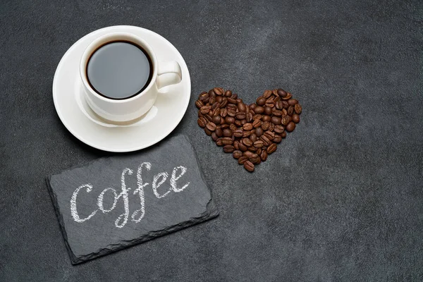 Filiżanka espresso i Serca w kształcie palonej ziarna kawy na ciemnym tle betonu — Zdjęcie stockowe