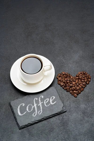 Filiżanka espresso i Serca w kształcie palonej ziarna kawy na ciemnym tle betonu — Zdjęcie stockowe