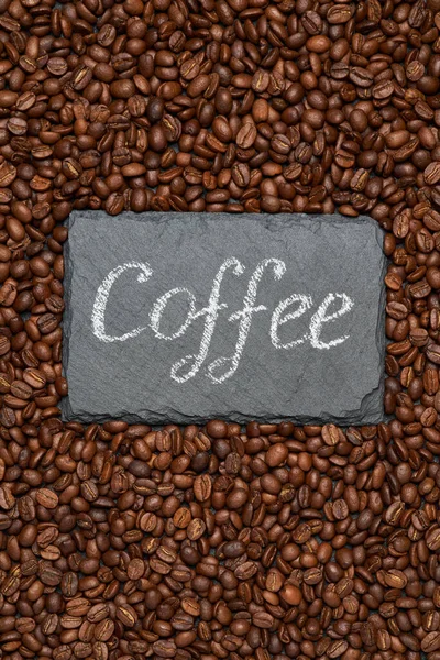 Background or texture made of roasted brown coffee beans and stone serving board with chalk handwritten sign — Stock Photo, Image