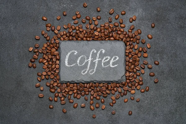 Hintergrund oder Textur aus gerösteten braunen Kaffeebohnen und Steintafel mit handgeschriebenem Kreideschild — Stockfoto