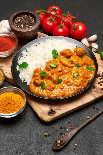 Teller mit traditionellem Chicken Curry, Reis und Gewürzen auf dunklem Betongrund — Stockfoto
