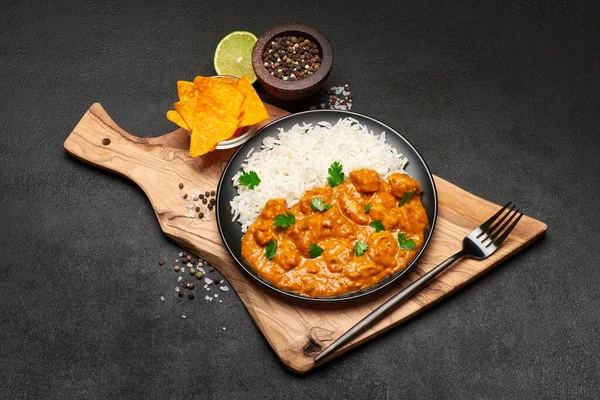 Teller mit traditionellem Chicken Curry, Reis und Gewürzen auf dunklem Betongrund — Stockfoto