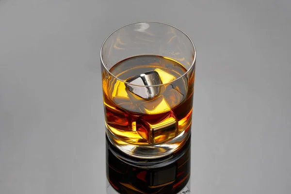 Whiskey with steel cooling cubes on dark glass background — Stock Photo, Image