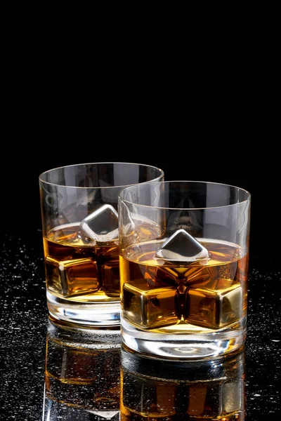 Whiskey with steel cooling cubes on dark glass background — Stock Photo, Image