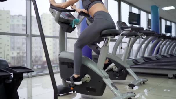 年轻女子骑自行车在健身房锻炼 — 图库视频影像