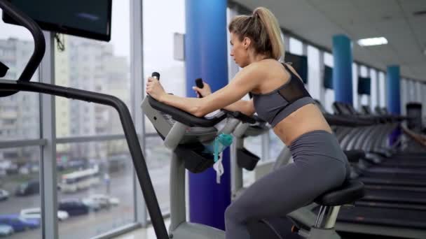 Ung kvinna på cykel på gym träning — Stockvideo