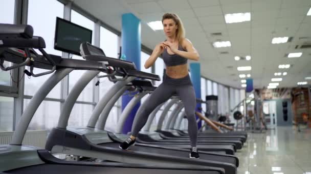 Jonge sportieve vrouw op de lopende machine in Gym — Stockvideo