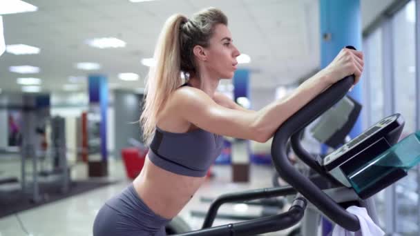 Молодая женщина тренируется на ступеньках в тренажерном зале — стоковое видео