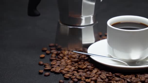 Чашка кави еспресо та кавоварки моча на смажених кавових зернах коричневого кольору на бетонному фоні — стокове відео
