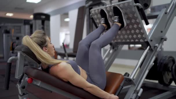 Mulher apta a praticar agachamentos nas costas na máquina de exercício — Vídeo de Stock