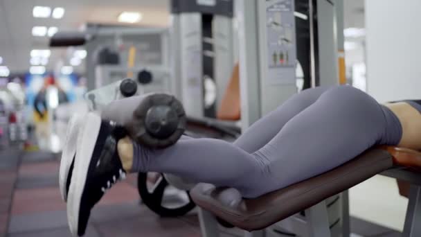 Νέα σπορ γυναίκα οικοδόμηση των μυών των ποδιών σε ένα μηχάνημα κατάρτισης στο γυμναστήριο — Αρχείο Βίντεο