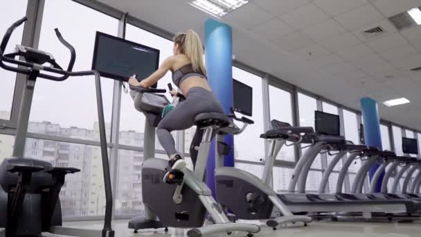 Молода жінка на велосипеді в тренажерному залі — стокове відео
