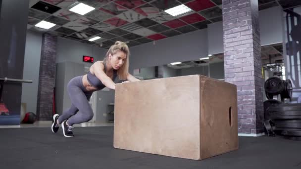 Hermosa joven mujer deportiva haciendo flexiones en la caja de ajuste en el gimnasio — Vídeo de stock