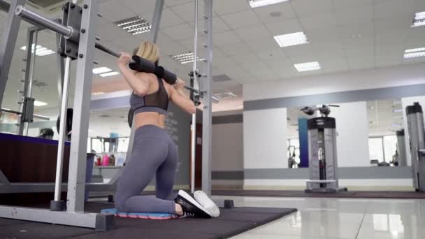 Joven mujer deportiva haciendo algunas sentadillas con una barra — Vídeos de Stock