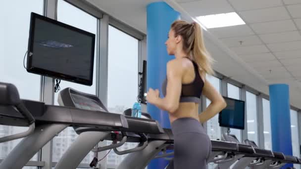 Joven mujer deportiva en la máquina en el gimnasio — Vídeo de stock