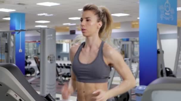 Junge sportliche Frau auf Laufmaschine in Turnhalle — Stockvideo
