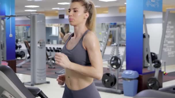 Jonge sportieve vrouw op de lopende machine in Gym — Stockvideo