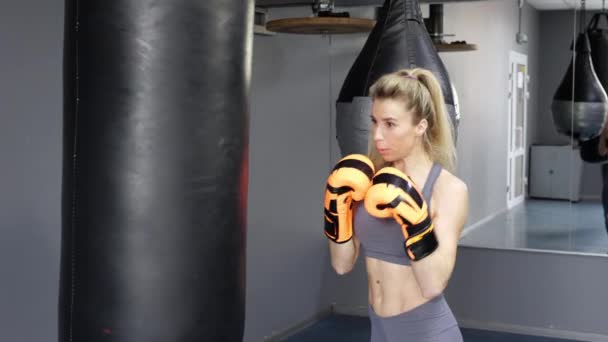 Ökölvívó kesztyűt viselő fiatal nő boksz edzést tart az edzőteremben. — Stock videók