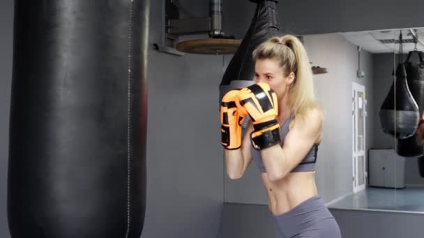 Ung kvinna i slaghandskar som tränar boxning på gymmet — Stockvideo