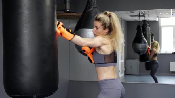 Молода жінка носить ударні рукавички, навчаючись боксу в спортзалі — стокове відео