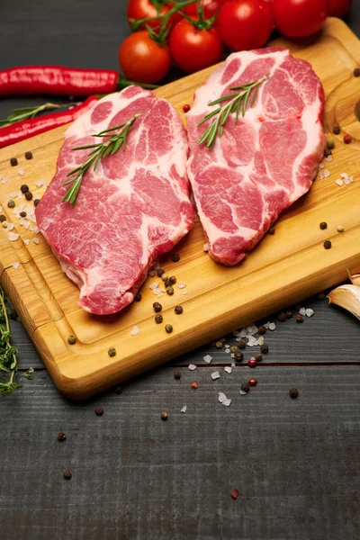 Steaks de bœuf ou de porc frais crus sur planche à découper en bois — Photo